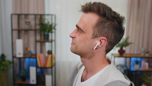 Giovane con un auricolare che guarda lontano a casa