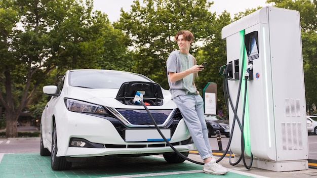 Giovane con un'auto elettrica alla stazione di ricarica a Chisinau Moldova