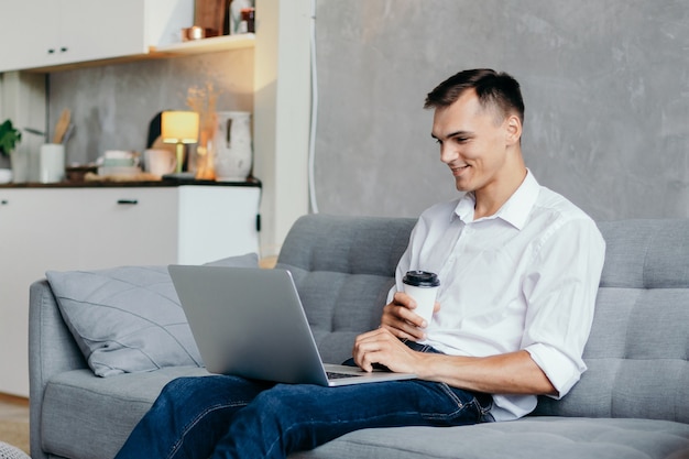 Giovane con una bevanda calda che sfoglia le notizie su Internet. vita domestica.