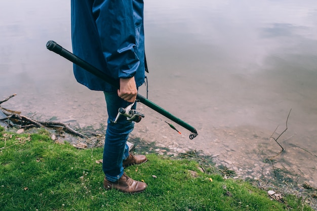 Giovane con una canna da pesca in piedi sul lago