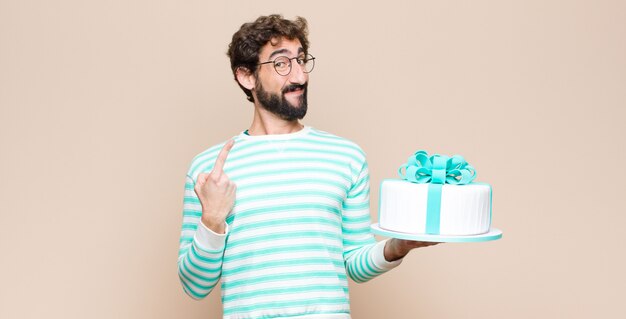 Giovane con una torta contro la parete piana