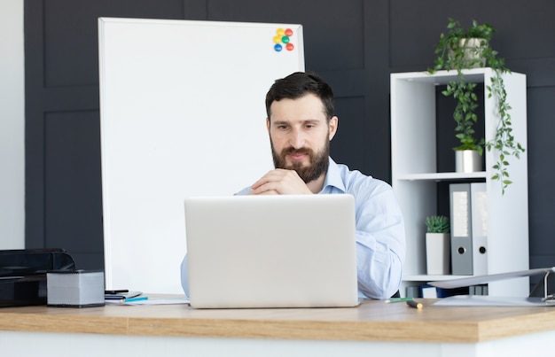 Giovane concentrato che lavora al computer portatile in ufficio a casa