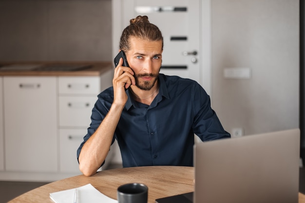 Giovane concentrato che parla al cellulare e guarda la telecamera