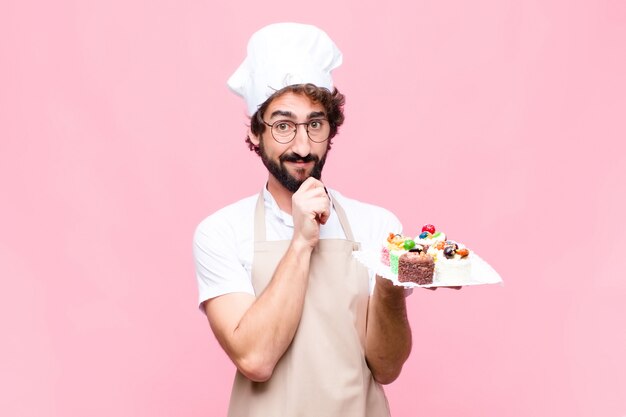 Giovane concetto pazzo della confetteria dell'uomo del panettiere sulla parete rosa