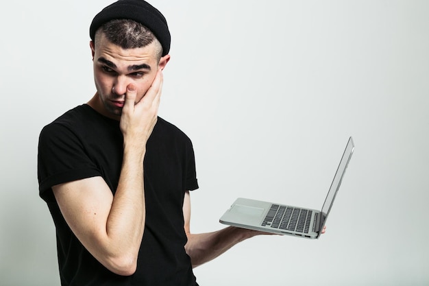 Giovane confuso con il computer portatile in studio