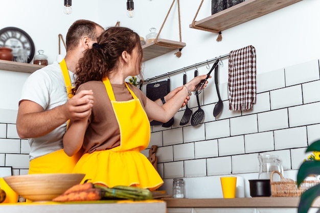 Giovane coppia adorabile che cucina un piatto in cucina e si abbraccia