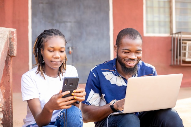 Giovane coppia africana caucasica sorridente felice utilizzando laptop e smartphone pagando la fattura online tramite banca mobile