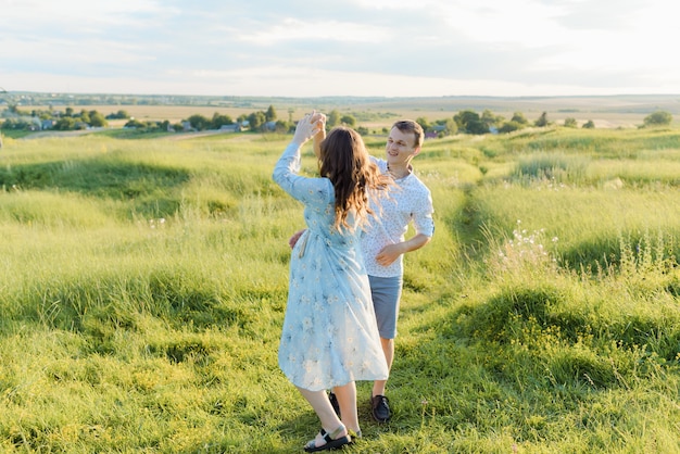 Giovane coppia allegra di un uomo e di una donna all'aperto in un campo, abbracciare e ballare. Foto di alta qualità