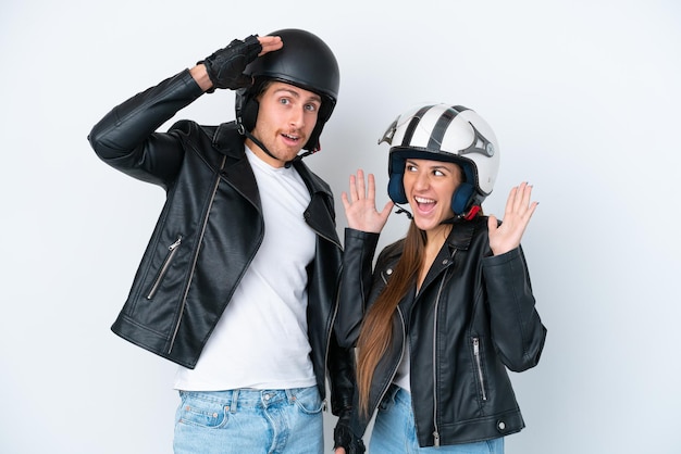Giovane coppia caucasica con un casco da motociclista isolato su sfondo bianco con espressione facciale sorpresa e scioccata