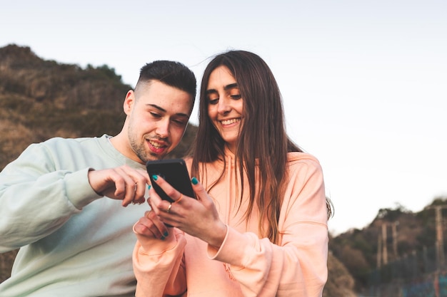 Giovane coppia caucasica utilizzando uno smartphone sulla natura