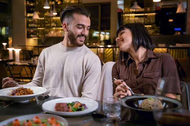 Giovane coppia che cena al ristorante fusion - coppia di giovani amanti che mangiano cibo asiatico - coppia romantica seduta al ristorante - concetto di stile di vita