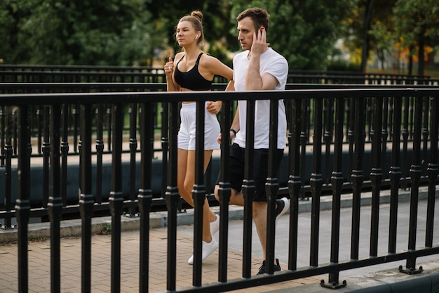 Giovane coppia che corre nel parco cittadino, sport congiunti, allegria, stile di vita cittadino city