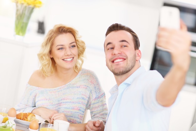 giovane coppia che fa colazione in cucina e si fa selfie