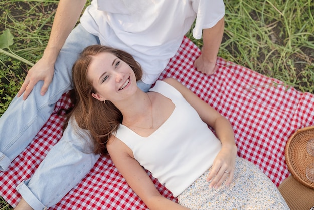 Giovane coppia che fa un picnic sul campo di girasoli al tramonto