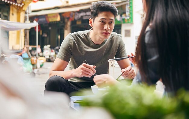 Giovane coppia che mangia cibo vietnamita in strada