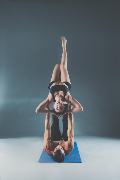 Giovane coppia che pratica acro yoga sul tappetino in studio insieme Acroyoga Yoga di coppia Partner yoga