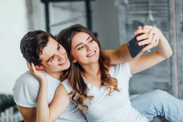 Giovane coppia che si diverte a fare selfie insieme a letto la mattina