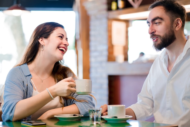 Giovane coppia che si diverte bevendo una tazza di caffè insieme in una caffetteria.