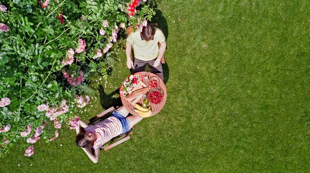 Giovane coppia che si gode cibo e bevande nel bellissimo giardino di rose in una romantica vista aerea