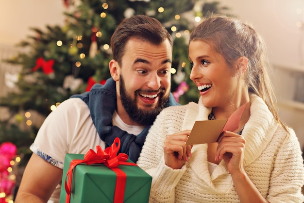 giovane coppia con un regalo sull'albero di Natale Christmas