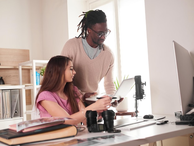 Giovane coppia di fotografi che lavorano con il laptop sul posto di lavoro con due computer in studio