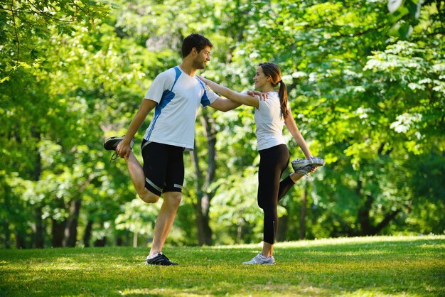 giovane coppia di salute che fa esercizio di stretching rilassante e riscaldarsi dopo aver fatto jogging e corsa nel parco