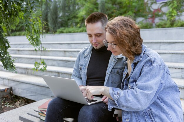 Giovane coppia di studenti che trascorrono del tempo a studiare insieme al computer portatile all'aperto
