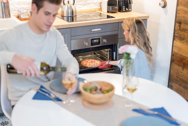 giovane coppia felice che cena a casa e una giovane bella donna bionda che prende una pizza sfornata