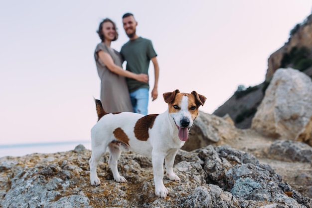 Giovane coppia felice con un cane sulla spiaggia Bella famiglia e cucciolo jack russell terrier