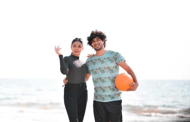 giovane coppia felice posa anteriore tenendo il calcio sulla spiaggia modello pakistano indiano