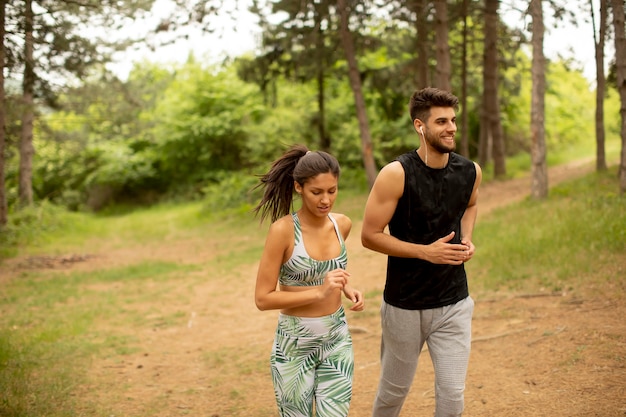 Giovane coppia fitness che corre lungo il sentiero nel bosco in una giornata estiva