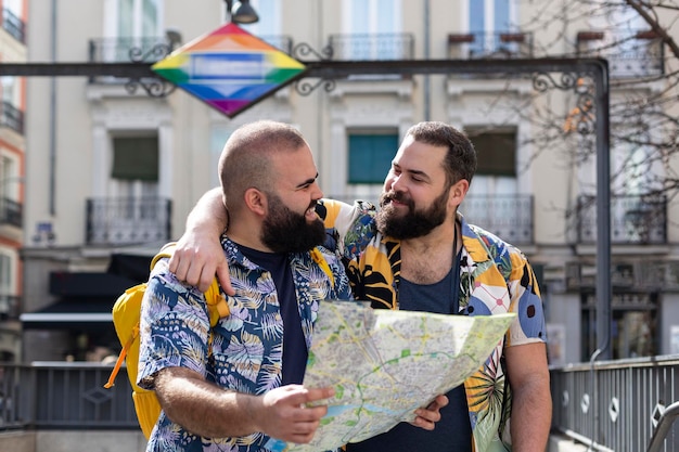 Giovane coppia gay con mappa turistica all'uscita di una stazione di trasporto Concetto di persone che viaggiano e vacanze