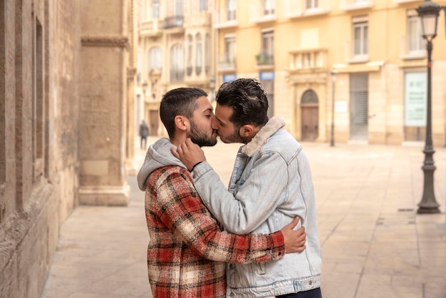 Giovane coppia gay innamorata che abbraccia e bacia in strada