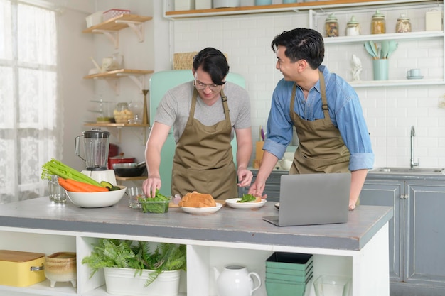 Giovane coppia gay sorridente che cucina insieme in cucina a casa LGBTQ e concetto di diversità