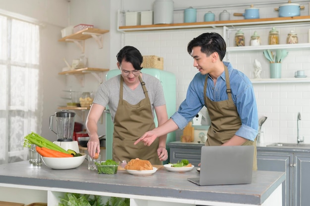 Giovane coppia gay sorridente che cucina insieme in cucina a casa LGBTQ e concetto di diversità