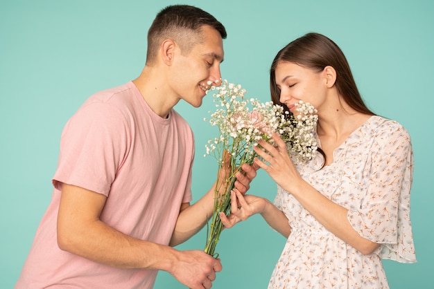 giovane coppia in abiti casual tenendo insieme bouquet e fiori profumati con gli occhi chiusi