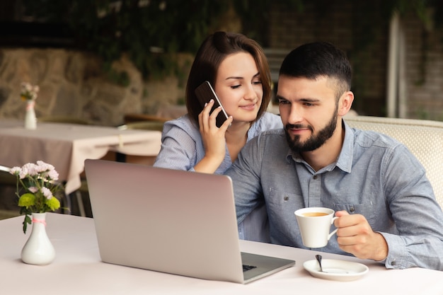 Giovane coppia in amore, lavorando da casa, uomo e donna seduta al tavolo, lavorando sul portatile in casa