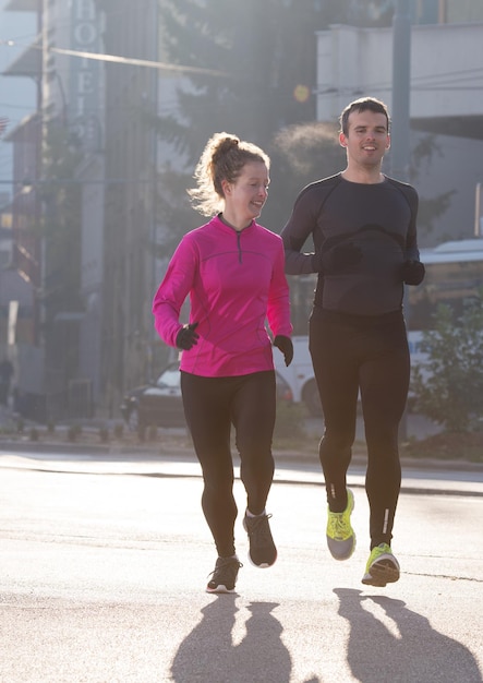 giovane coppia in buona salute che fa jogging in città al mattino presto con l'alba sullo sfondo