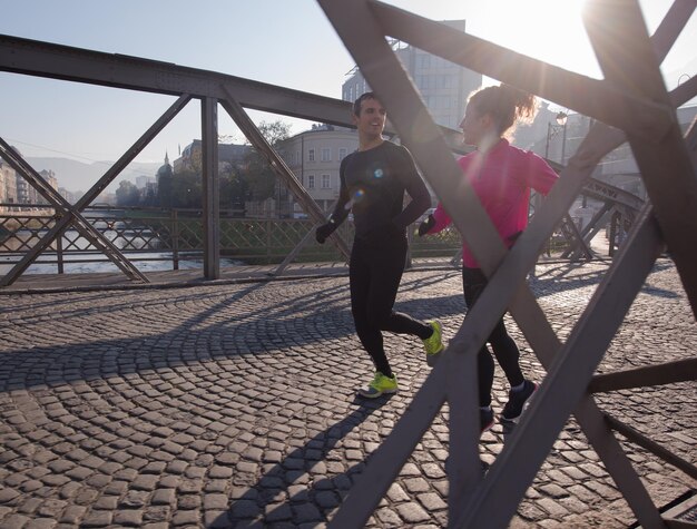 giovane coppia in buona salute che fa jogging in città al mattino presto con l'alba sullo sfondo