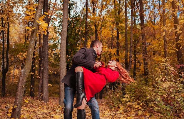 Giovane coppia innamorata che balla nella foresta autunnale tra alberi colorati