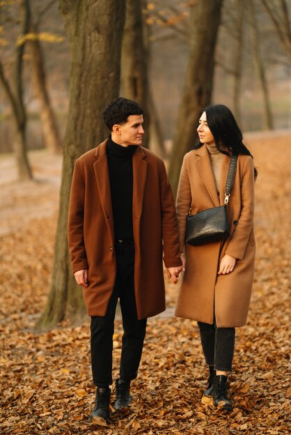 Giovane coppia innamorata che cammina nel parco in una giornata autunnale