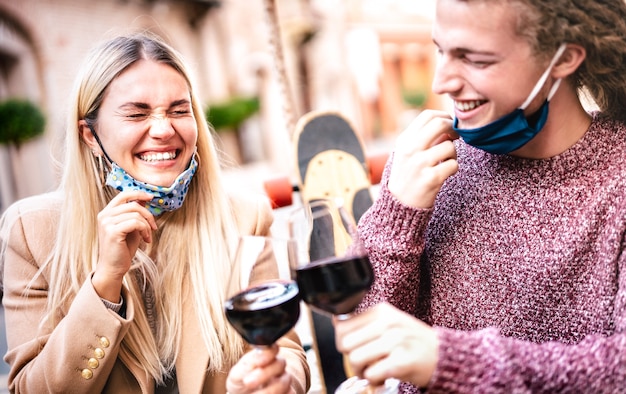 Giovane coppia innamorata che indossa maschere facciali aperte e divertirsi al bar della cantina all'aperto - Focus sulla donna di sinistra