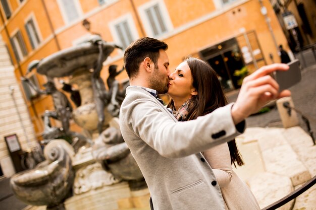 Giovane coppia innamorata che si bacia e prende selfi a Roma