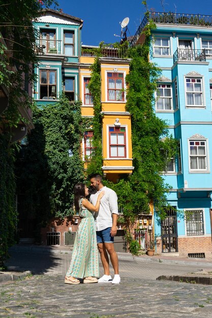 Giovane coppia innamorata su una strada di Istanbul che abbraccia e sullo sfondo edifici colorati con piante