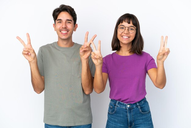 Giovane coppia isolata su sfondo bianco isolato sorridente e mostrando il segno di vittoria con entrambe le mani