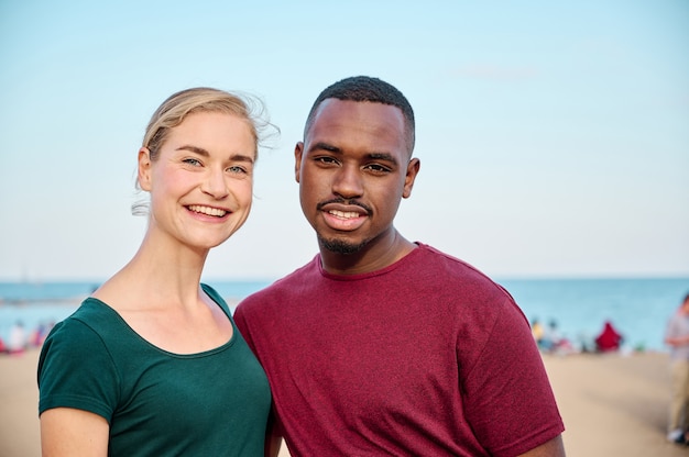 giovane coppia multietnica che guarda l'obbiettivo in spiaggia