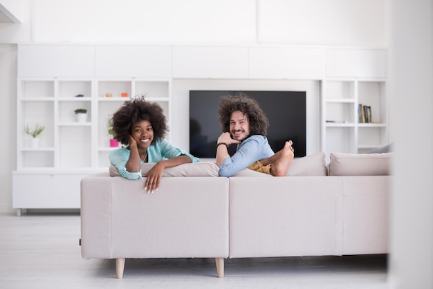 Giovane coppia multietnica seduta su un divano nel soggiorno di lusso