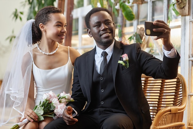 Giovane coppia nera come sposa e sposo che scattano foto selfie