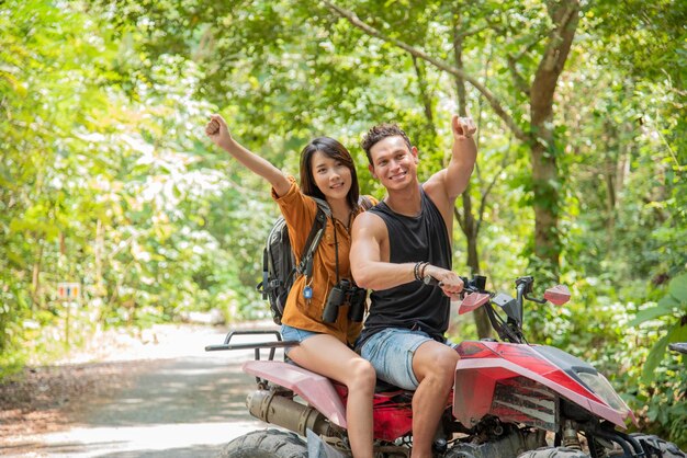 Giovane coppia o amico felice mentre guida un ATV nella foresta