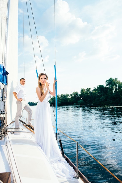 Giovane coppia ragazzo e ragazza su uno yacht a vela bianco